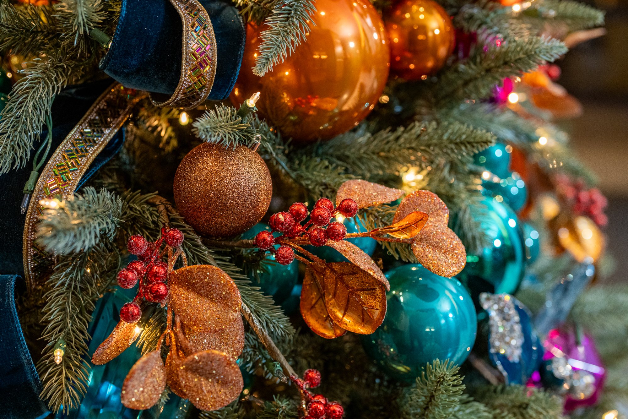 Meticulous styling detail: glittered copper leaves placed among teal ornaments and warm lights