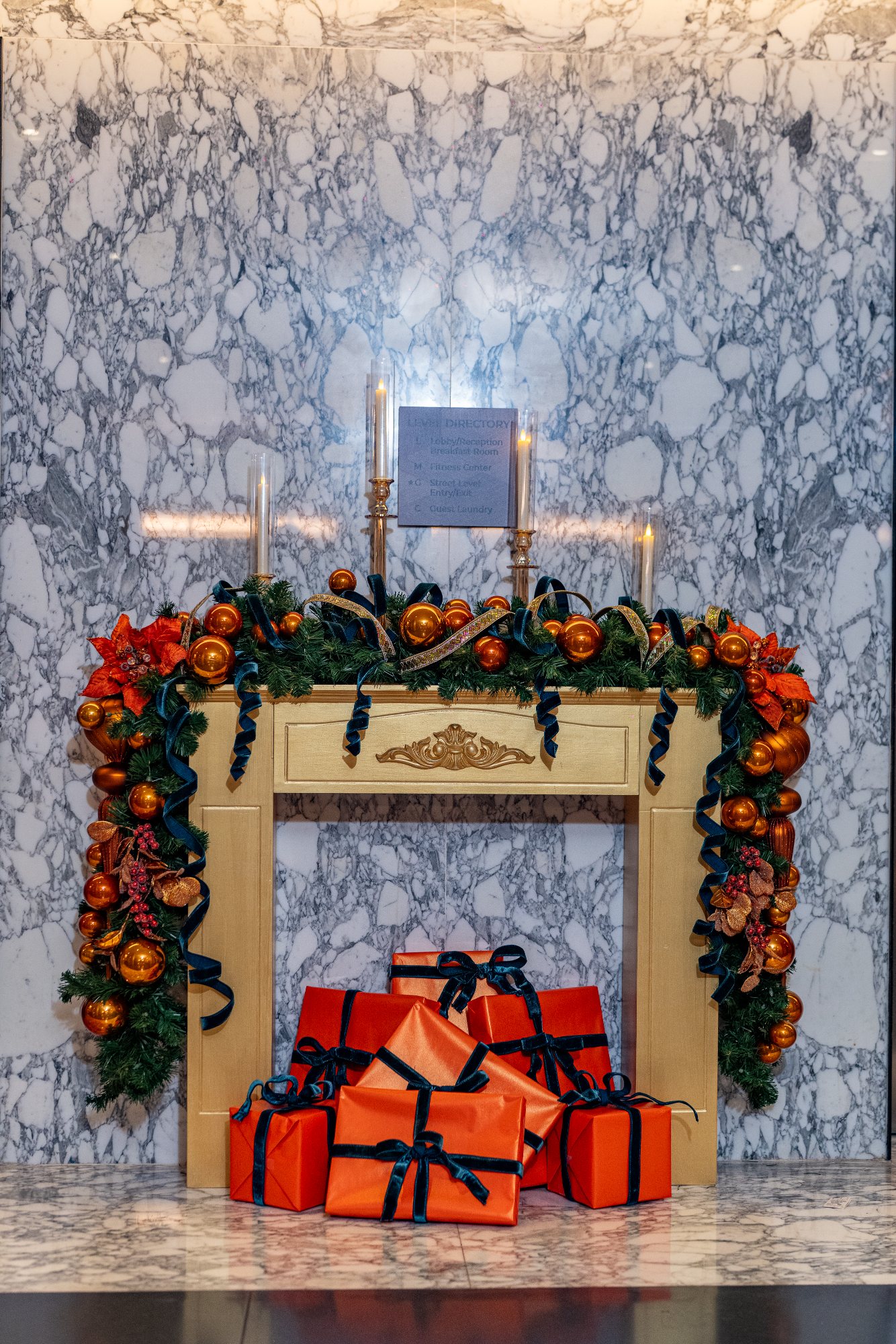A styled hearth: gilded fireplace, ornament garland, and coordinated gifts