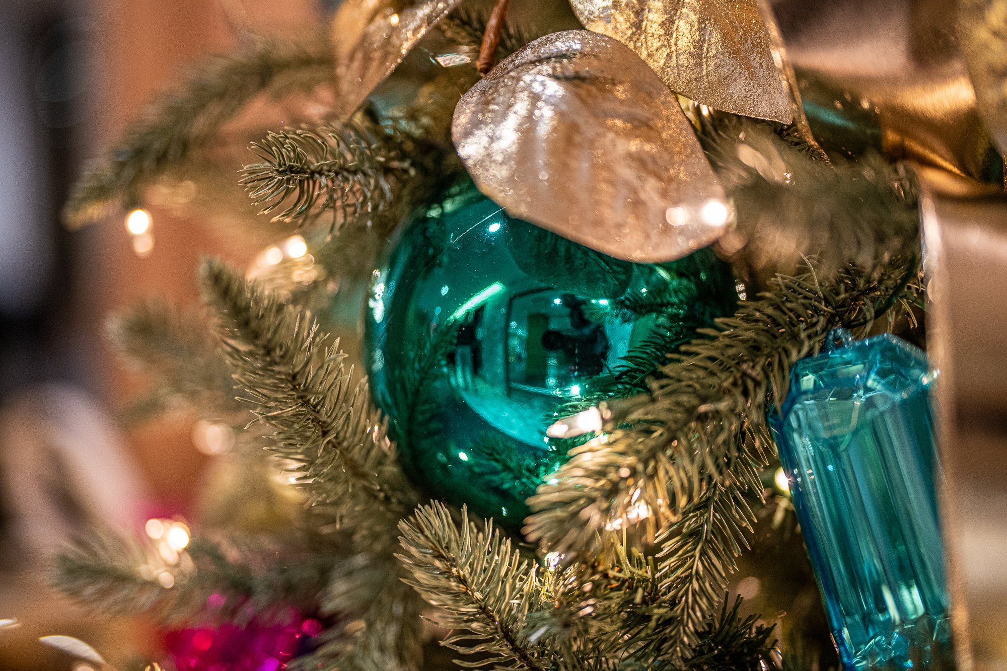 Monogrammed teal glass ornament with gilded leaves on the jewel-tone tree