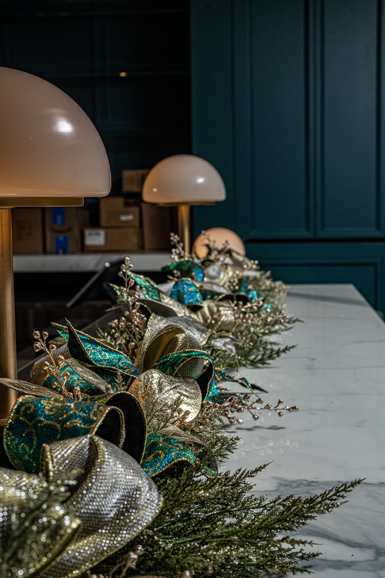 Emerald and gold garland runner with jeweled ribbon and greenery styled along a marble reception counter