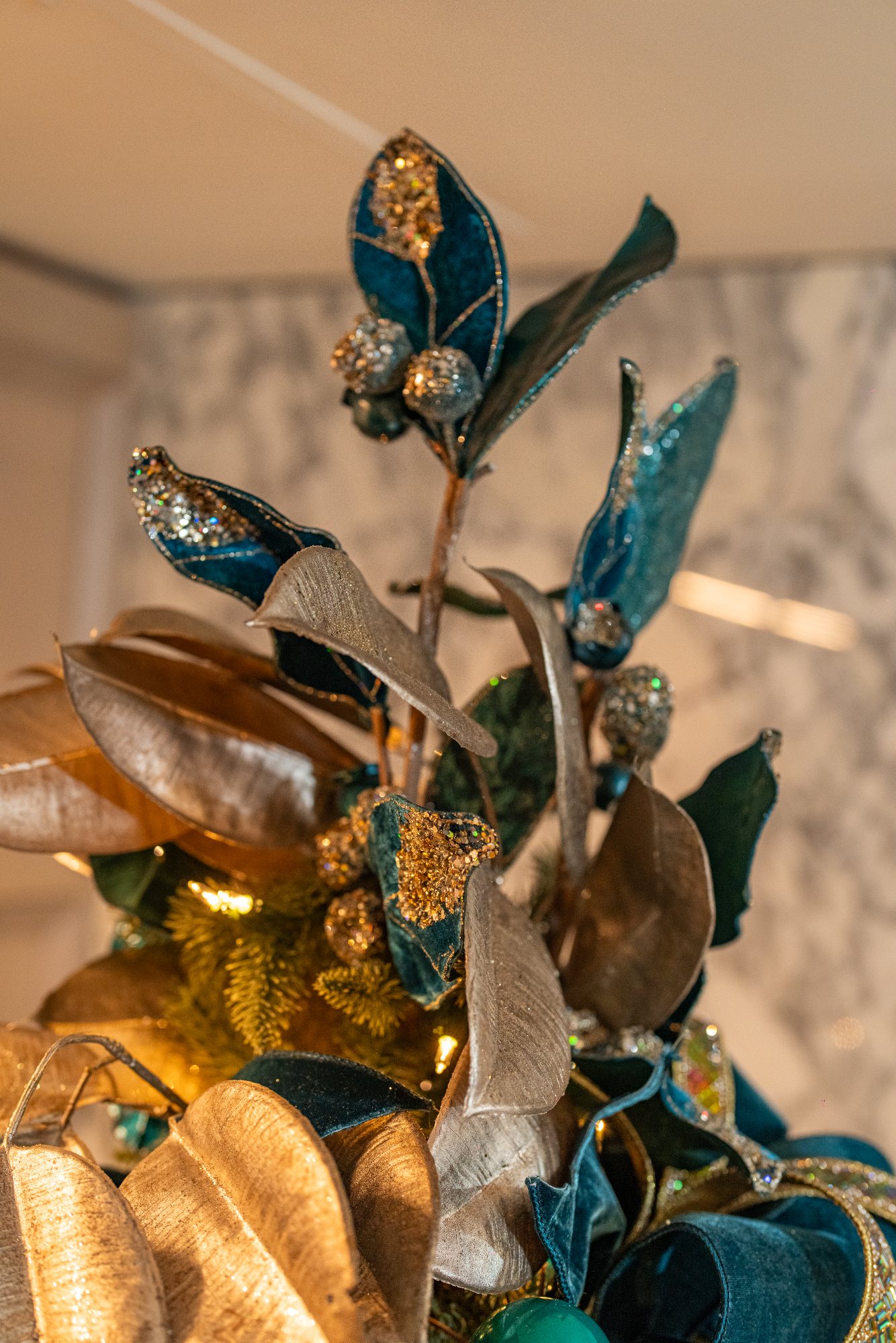 Tree topper of teal velvet and gilded magnolia leaves with crystal berries